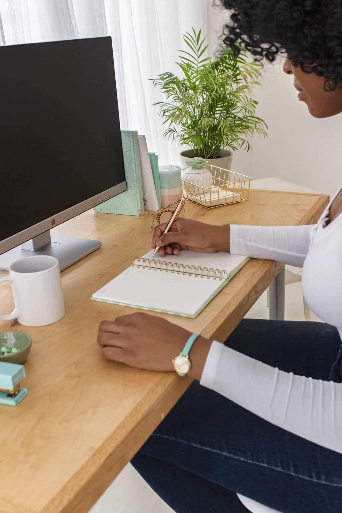 photo of a woman sitting at a desk, writing in a notebook