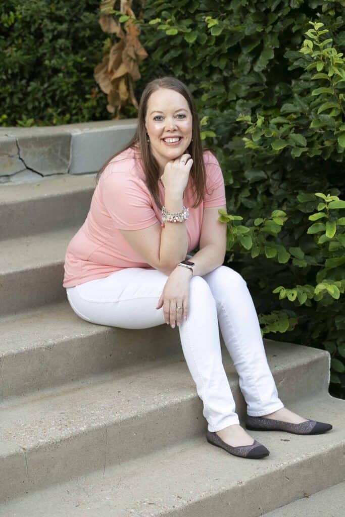 Intensive 13 Melissa Mackey, branding and web design for ADHD entrepreneurs, sitting outdoors on some stairs, smiling at the camera, wearing a pink shirt