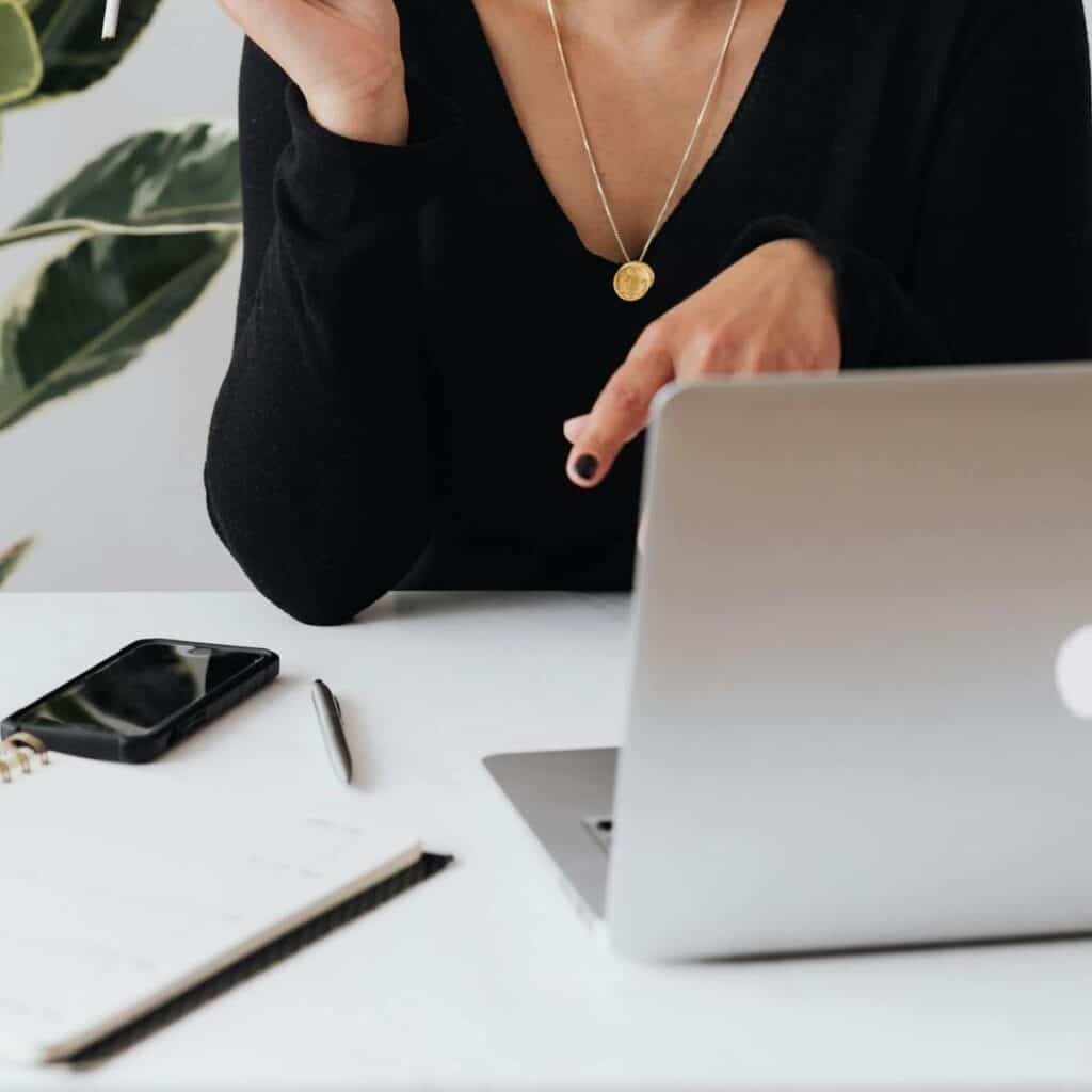 Black Friday Sale 2 concentrated female in formal black wear having conversation via video call on laptop while working at table and smoking cigarette against white wall 4467682 scaled 1